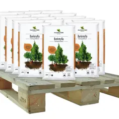 Sju säckar Barkmylla från Hasselfors Garden står på en träpall, redo att luckra upp jord och ge näring till dina växter.
