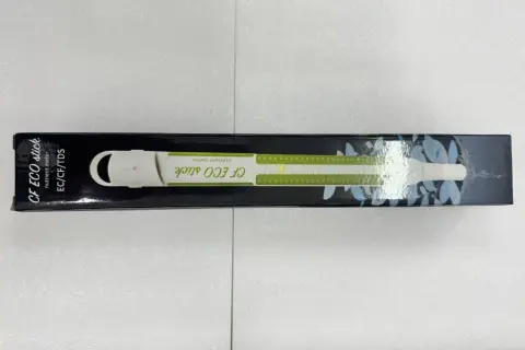 En vit ec mätare, CF ECO stick, ligger i sin svarta förpackning med gröna markeringar och bladmotiv.