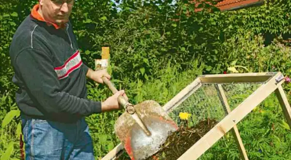 Man skopar kompost i en sil. Egen kompost ger näringsrik jord till trädgården.