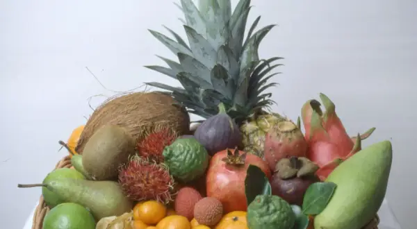 En korg fylld med exotiska frukter, inklusive en ananas som ser ut att vara redo att plantera.