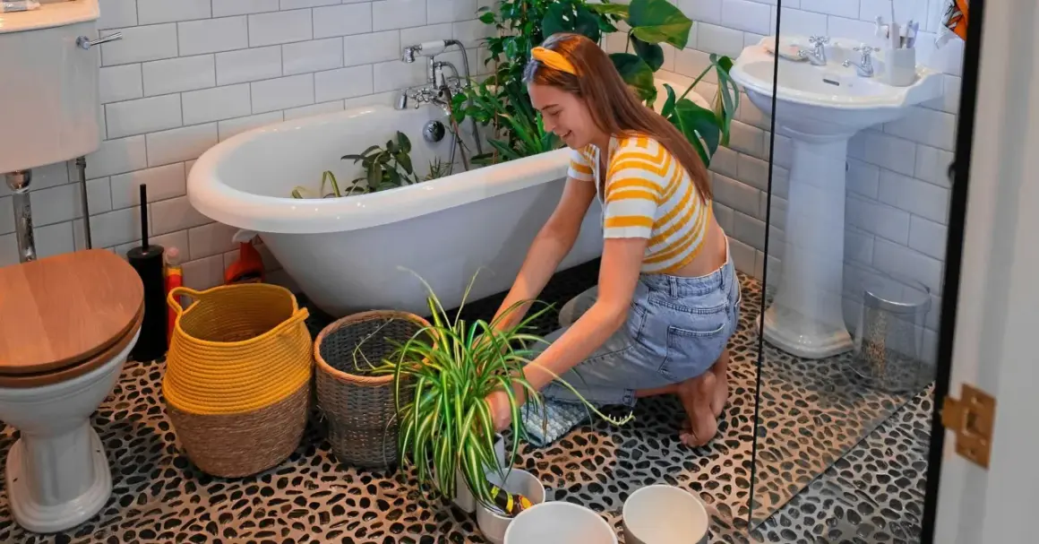 En ung kvinna vattnar blommor i badkaret, en mysig semesteraktivitet.