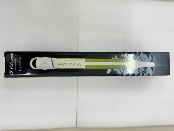 En vit ec mätare, CF ECO stick, ligger i sin svarta förpackning med gröna markeringar och bladmotiv.
