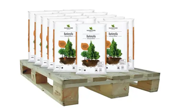Sju säckar Barkmylla från Hasselfors Garden står på en träpall, redo att luckra upp jord och ge näring till dina växter.